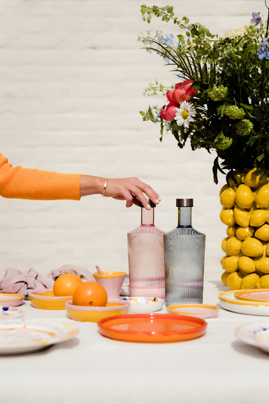 a hand grabbing one of the two handcrafted glass carafes on a table