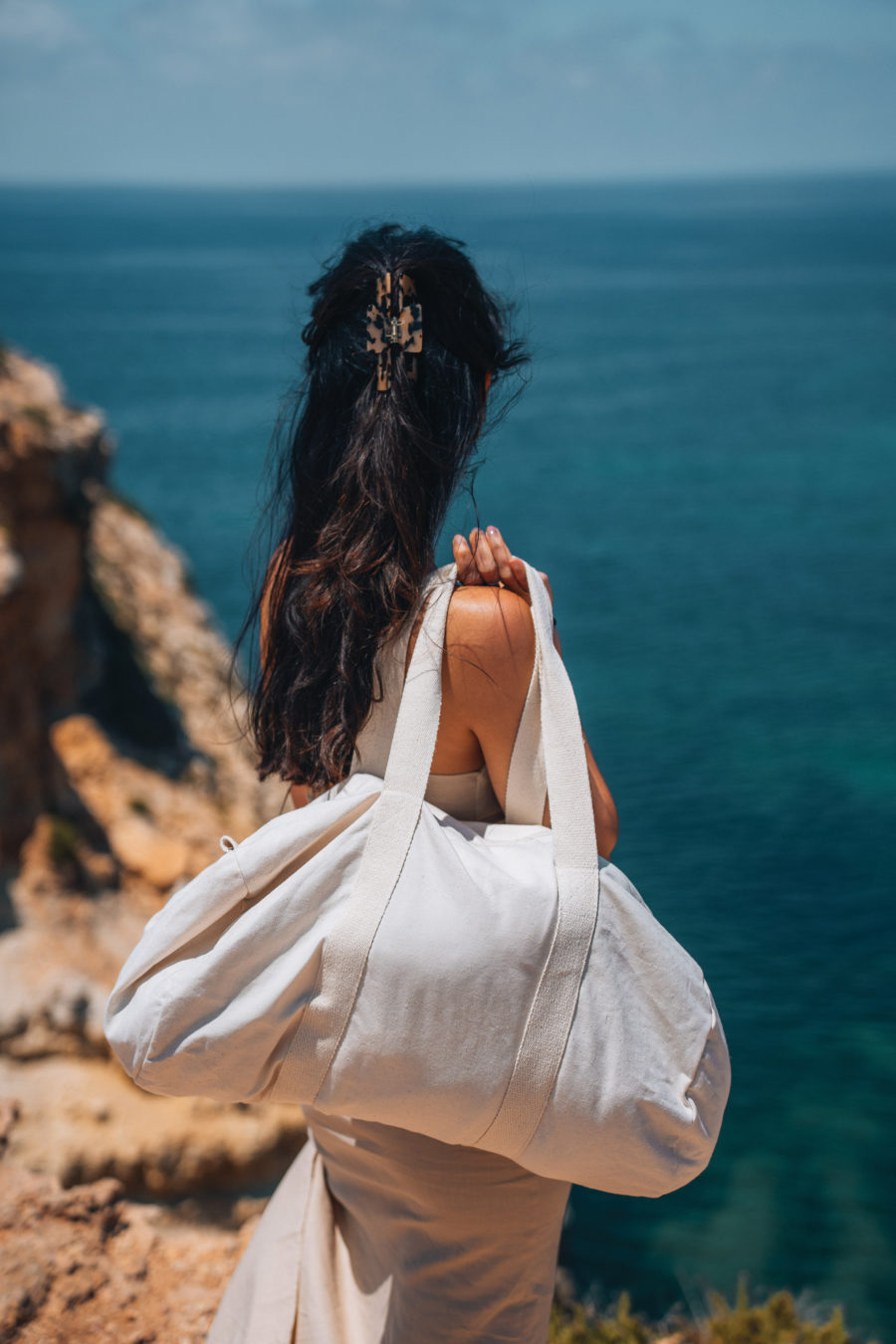 woman looking at the sea and wearing a duffel bag