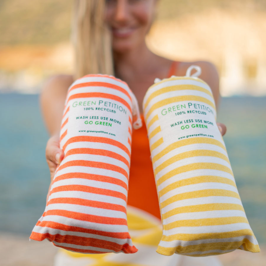 woman showing two stripped beach towels, one orange and one yellow