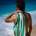 a man from the back with a lime stripped beach towel